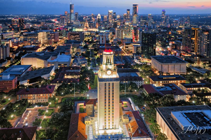 Aerial view of the University of Texas Tower with the Austin skyline behind at dusk