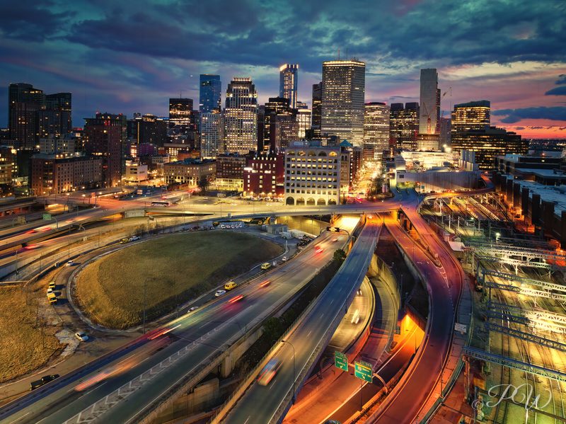 Aerial view of the Boston skyline with light trails on the roads below at dusk