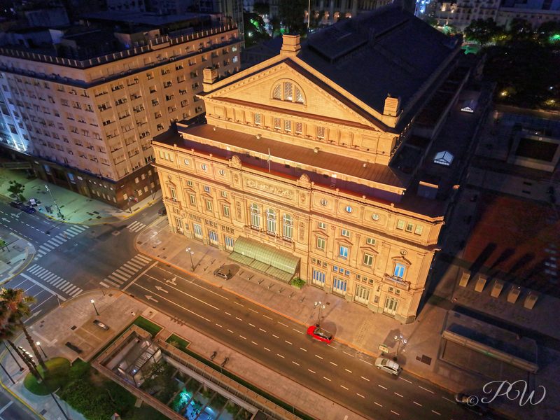 Aerial view of a large ornate historic building on a city block at dusk