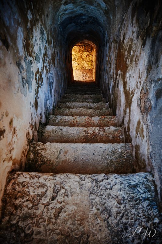 A narrow stone stairway climbs through a vaulted passage inside El Morro Castle