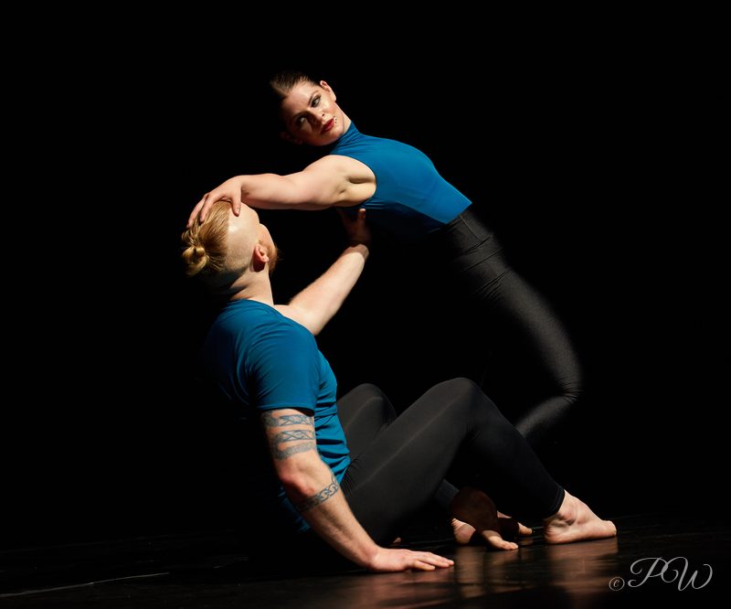 Two dancers in blue tops in a close floor duet