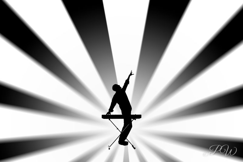 A performer silhouetted on a stand against a black and white sunburst backdrop