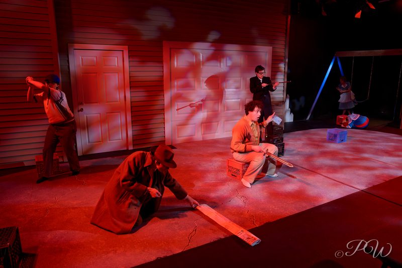Actors spread across a stage set washed in red light