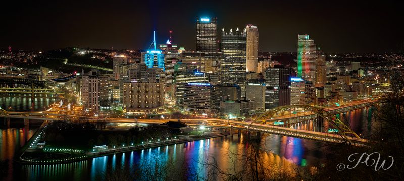 The Pittsburgh skyline and bridges reflected in the river at night