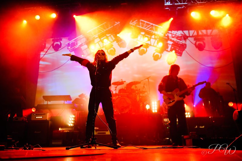 El Monstero on stage with arms spread against bright orange and red stage lights