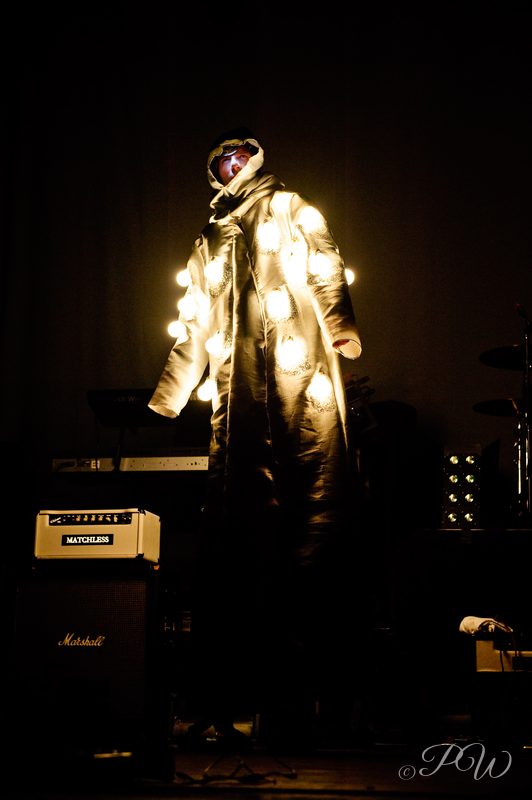 A performer in a costume covered in lights on a dark stage