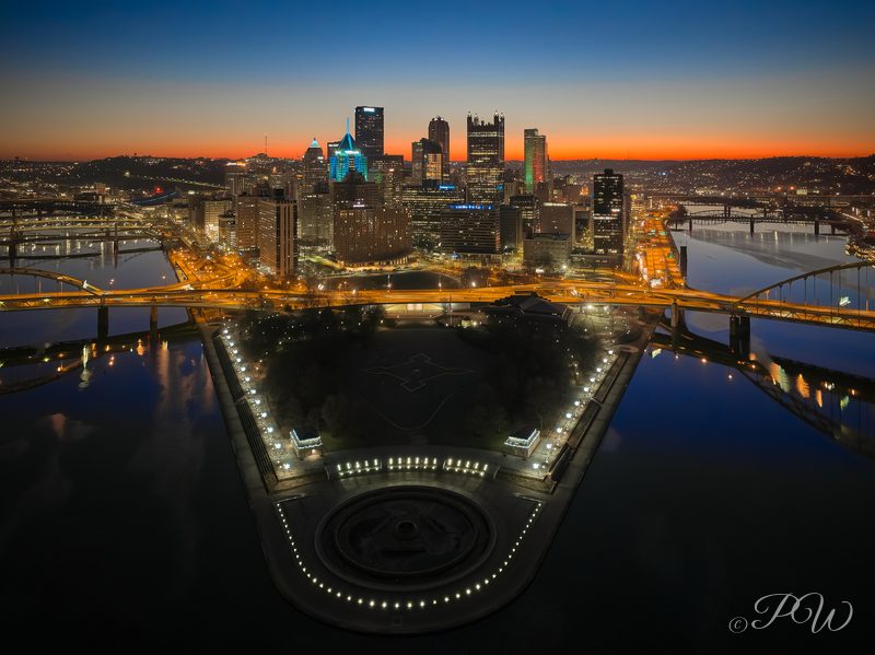 Aerial view of the park at the point where Pittsburgh's rivers meet, with downtown at dusk