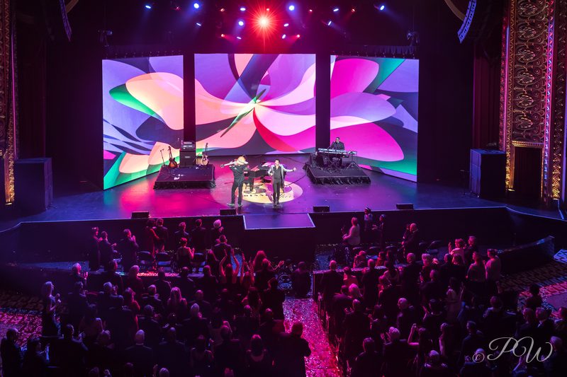 A gala stage with a giant lotus image on the screen above the audience