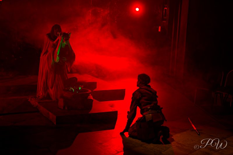 Figures on a stage lit in deep red