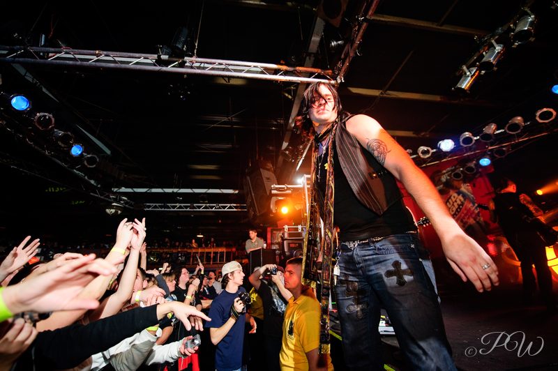 Hinder's singer leans over a crowd of raised hands at Pop's nightclub