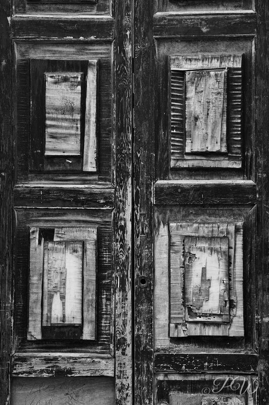 A weathered panelled wooden door in black and white