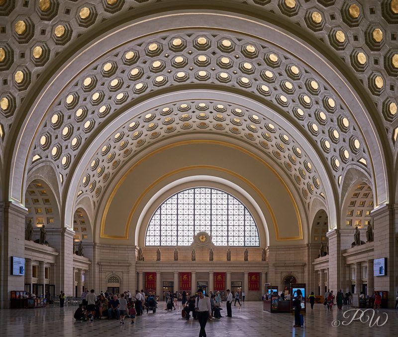 A grand hall with a coffered barrel vault and arched window